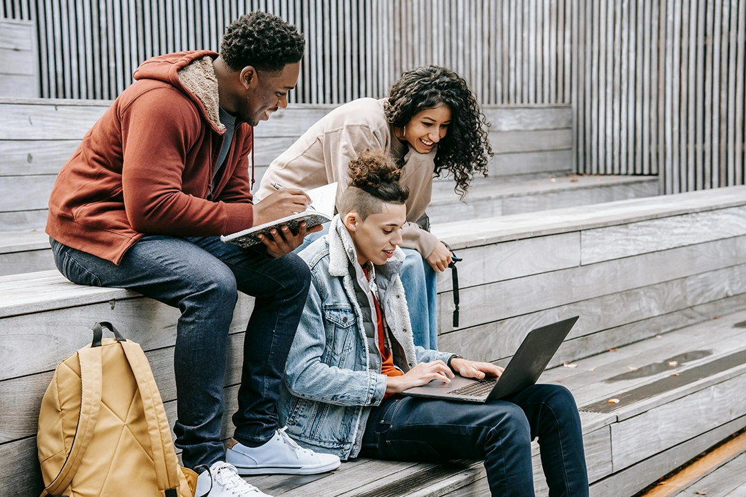 Three people working together while sitting on outdoor stairs